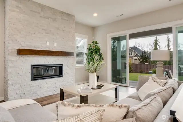 Great room with electric fireplace and wall of glass nesting doors to spacious covered patio/deck.
