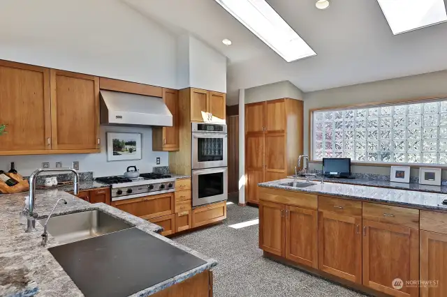 Kitchen - Viking cooktop, LG double convection ovens, Cherry wood cabinets, wet bar sink, indoor grill, Sub Zero refrigerator, Bosch dishwasher, granite countertops. Workspace in the background. Skylight above.