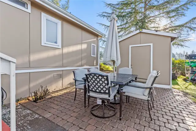 charming back yard with extra storage shed and sweet patio for outdoor entertainment and raised garden beds behind home.