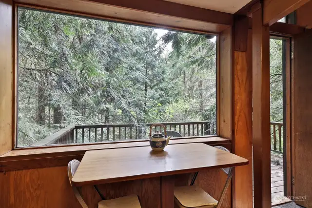 Dining area with a large window that frames the treed setting.