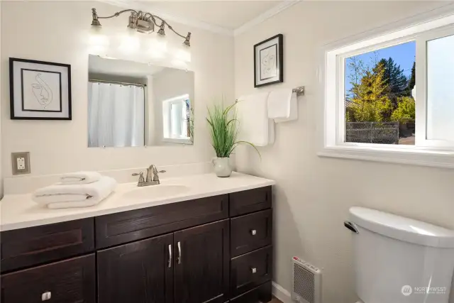 A large bathroom with an oversized vanity features a tile floor and full bathtub.