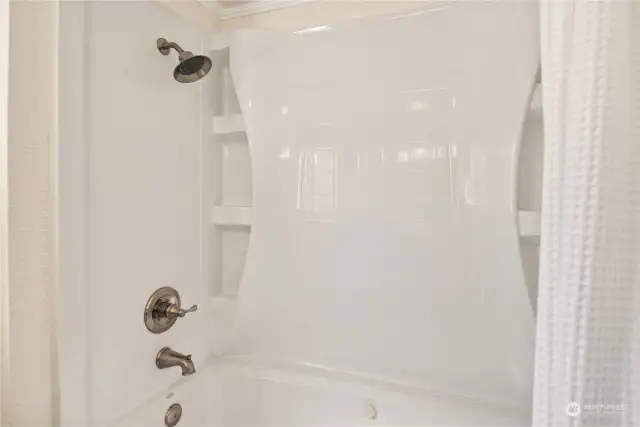 A picture of the bathtub in the cottage with new fixtures and surround.