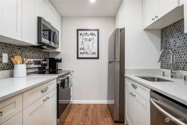 Sleek and modern this remodeled kitchen has everything you could want including, a crisp & clean quartz countertop, new faucet, deck mounted soap pump & aerator, stainless steel appliances and a full wall designer backsplash!
