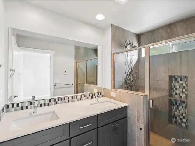 Primary bath 1 features dual sinks, custom tile shower surround & the same cool colors that is throughout the home.