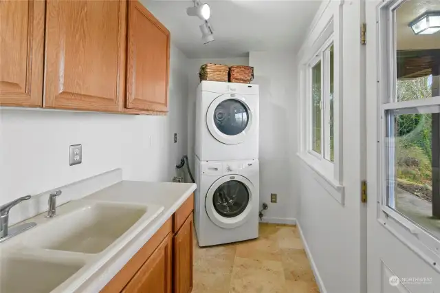 A lower level laundry room with plenty of storage, a double utility sink and an exterior door.