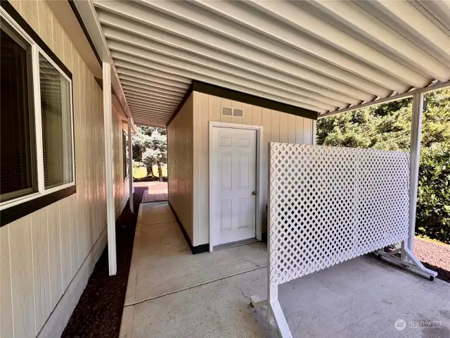 Out in the carport, the storage building and hallway to the backyard with 2 patios.