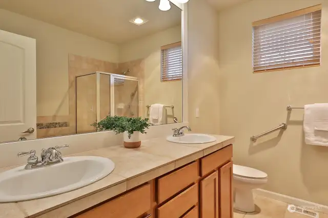 Primary full bath with porcelain tiled floor and countertops and maple vanity.