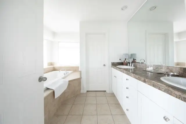 Primary bath with double sink vanity, limestone counters and soaking tub .