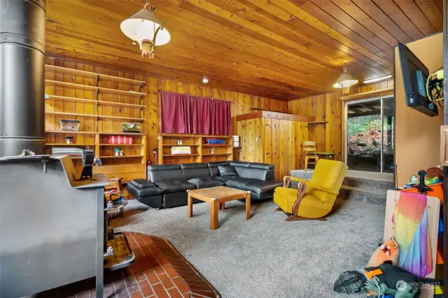 The family room features a wood stove on brick hearth, and slider to the covered back patio. There's plenty of shelving here for books or display. The original retro lighting really gives this room and inviting feeling.