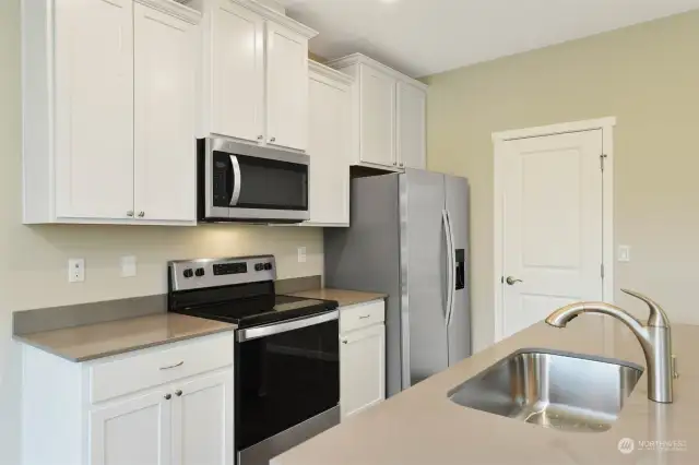 The kitchen features beautiful quartz counters, wood cabinetry, & brand-new appliances