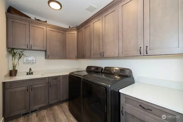 Laundry room with plenty of appealing storage choices, quartz counter tops, laundry sink and luxury vinyl plank floors! Who said laundry was a chore?