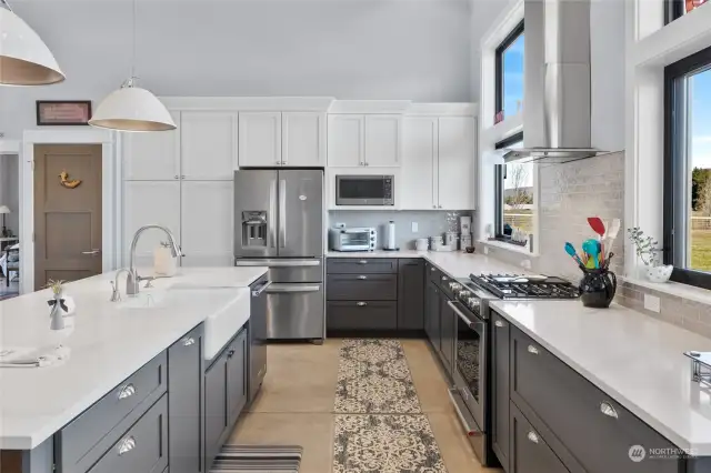 The stunning contemporary kitchen boasts granite countertops, an undermount sink, tiled backsplash, and stainless steel appliances including a 5-burner gas stove.