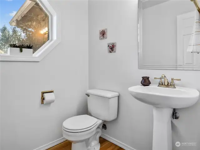 Here is the powder room that is located on the main floor of the home, features white oak hardwood floors and a classic pedestal sink.