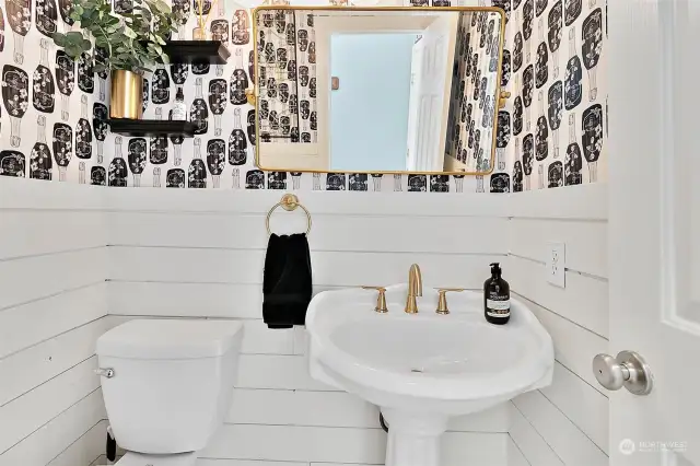 The updated guest / powder half bath is decorated with designer shiplap and located off the family room, near the man-door entrance to the 2-car attached garage with storage racks and overhead storage system.