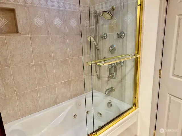 Hall bath with jetted tub and multiple shower heads.