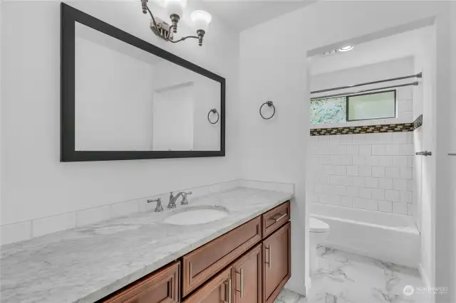 The main bathroom has tile accents, tile surround for the tub as well as tile flooring. The quartz counter really adds to the brightness. Newer fixtures here too!