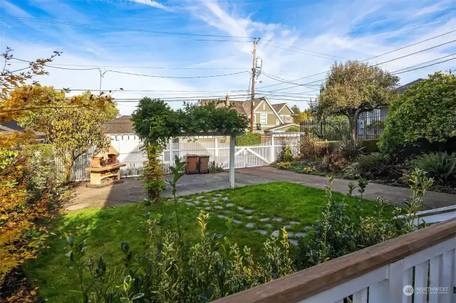 The professionally landscaped yard shines. You can get a peek at the pizza oven in the back and a space that can be used as off-street parking.