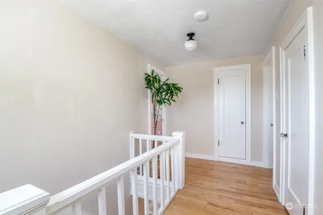 The upstairs landing. The first door is a powder room, the door straight ahead is the linen closet, and both bedrooms are to the left and right.