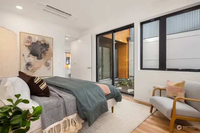 The main floor primary bedroom offers direct access to the private garden space through a large sliding glass door, creating a seamless connection between indoor comfort and outdoor tranquility.