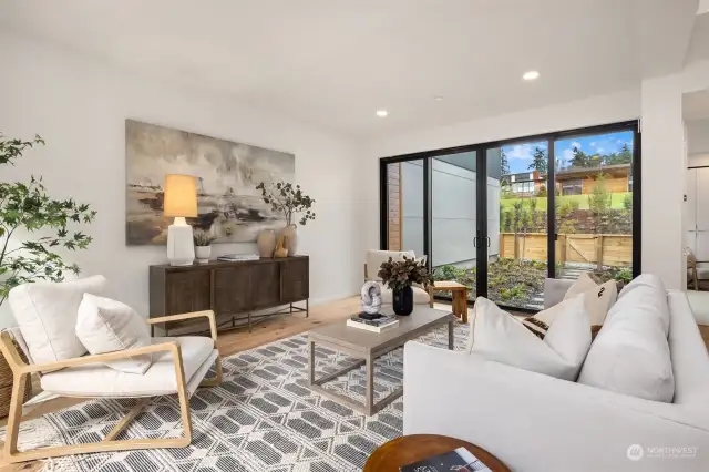 The spacious living room provides access to both the front patio and back garden through large sliding glass doors, creating a seamless indoor-outdoor flow that enhances the sense of space and natural light.