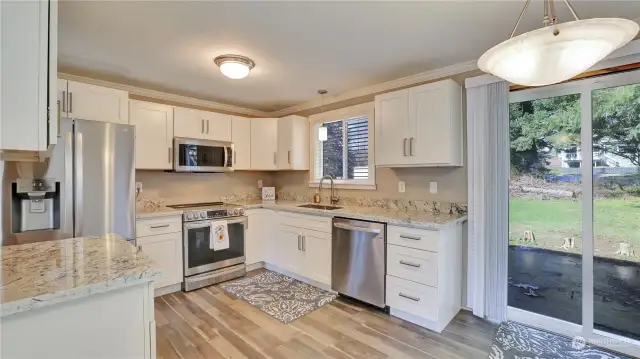 Kitchen boasts white shaker cabinets, stainless appliances and gorgeous countertops.