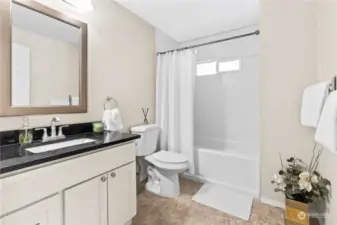 Main Full Bathroom, features quartz counter top, plenty of cabinet space for storage and newer tub enclosure.