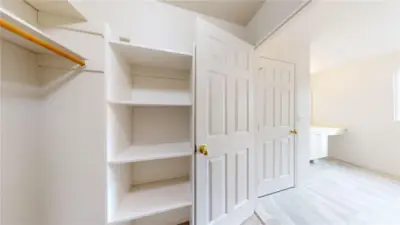 Primary walk-in closet has plenty of storage space and shelving.