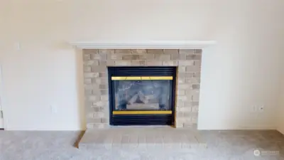 The living room boasts a gas fireplace with brick surround as the focal point.