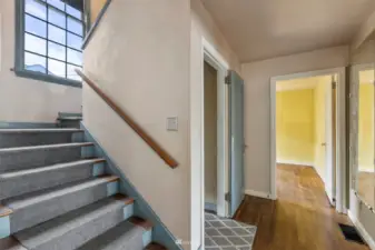 The stairway is between the entry and the main floor bedroom.