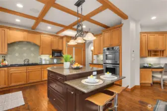 This kitchen comes equipped with a center island and eating bar, granite countertops, gas cooktop, prep sink, double ovens, an abundance of cabinetry, and a planning desk.