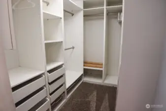 Primary bedroom boasts a large walk in closet featuring custom closet organizer