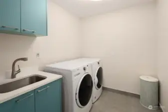 Main floor laundry with storage and deep stainless steel sink.