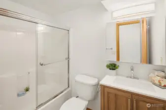Downstairs Full Bathroom with shower/tub with glass door, mirrored upper cabinet and  vanity.