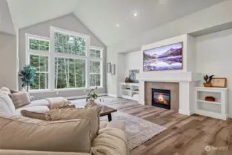 A shiplap feature wall and built-ins flank the gas fireplace and mantle, accenting the warm tone of beautiful engineered hardwoods.