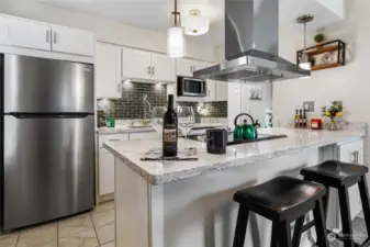 This Stunning custom kitchen remodel is simply breath taking.  Quartz counter tops, tile back spash, SS drop down hood vent, flat top stove, SS appliances, trendy lighting, Lots of white shaker cabinets and over hang for entertaining.  You will love this unit, this custom remodel is not like any other unit in the complex.
