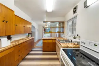Kitchen with original vinyl floors (so cute), wood cabinets with new butcher block counters, classic mid-century built-in display shelving unit and electric range.