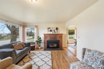 Spacious light-filled living room with gas fireplace, rounded archways and LVP flooring.