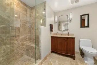Main floor guest bathroom with granite floor and shower with bench. Custom cabinets and stone top.