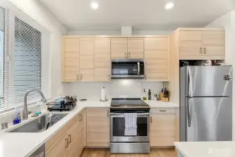 Upper unit kitchen. Quartz countertops, stainless appliances and modern cabinets and flooring.