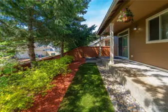 Low-maintenance backyard adorned with beautiful mature trees, bushes and artificial turf, providing a picturesque and hassle-free outdoor space.