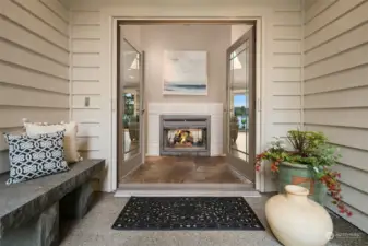 Step into a stunning entryway graced by a dramatic gas fireplace, offering a warm invitation to the inviting comfort of the main living room.