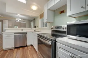Closer view of the kitchen with updated hardware, stainless steel appliances, and updated lighting.
