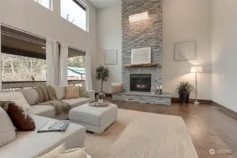 Enjoy this towering stone gas fireplace, stretching from floor to ceiling, adorned with a rustic wooden mantle and cozy seating area.