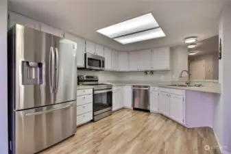 Kitchen view, love all the light, the flooring, pass-through window and included stainless steel appliances.