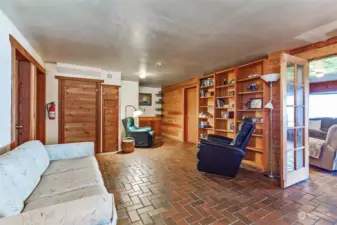 Lower level family room has built-in shelving & rustic Brick floors