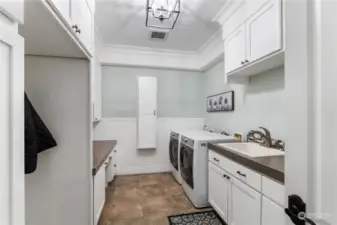 Laundry room is spacious with an ironing center, place for a freezer or extra refrigerator. Cabinets have lots of storage with built-in hamper, laundry sink, and desk area or counter for folding. The laundry is set-up for 2 washer and 2 dryers.