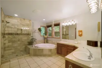 Primary bathroom features newly tiled and glass shower. Soaking tub and double sinks.
