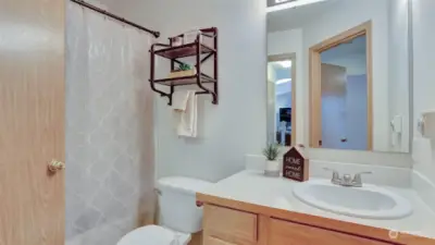 Bathroom features a shower/tub combination, storage space in the vanity and rustic hanging shelf.