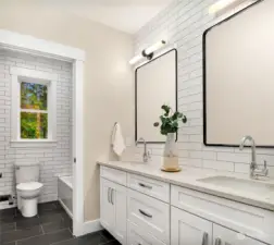 This full bathroom upstairs feels luxurious  with heated floors, the floor to ceiling tiled  wall, double sinks, and water closet.