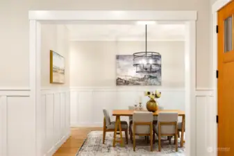 The dining room off the foyer is spacious  enough for a large table while still feeling  intimate. Wood floors, bay windows, crown  molding and wainscoting elevate the overall  feel in here. Host your holidays and  gatherings here, creating lifelong memories.